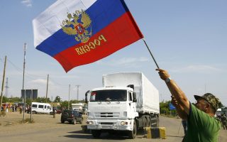 Ανεμίζοντας ρωσική σημαία υποδέχεται αυτός ο κάτοικος της Ανατολικής Ουκρανίας τη ρωσική αυτοκινητοπομπή με ανθρωπιστική βοήθεια.