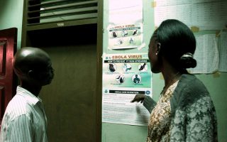 Liberian people read an information sign about Ebola set on a wall of a public health center on July 31, 2014 in Monrovia. Liberia announced on July 30 it was shutting all schools and placing 