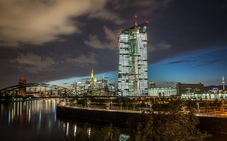 epa04455458 The new building of the European Central Bank ECB (R) is illuminated while dominating the skyline of Frankfurt, Germany, on 20 October 2014 evening. The ECB is scheduled to inform the public on the status of the construction works on 22 October 2014.  EPA/FRANK RUMPENHORST