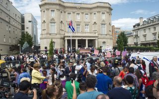 Εκπρόσωποι των ΜΜΕ και περαστικοί παρακολουθούν την έπαρση της κουβανικής σημαίας στη νέα πρεσβεία της χώρας στην Ουάσιγκτον, σε μία συμβολική κίνηση που σηματοδοτεί μία νέα μεταψυχροπολεμική εποχή στις σχέσεις Ηνωμένων Πολιτειών και Κούβας.