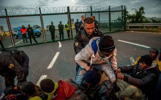 Παράνομοι μετανάστες στο Καλαί απομακρύνονται από αστυνομικούς μπροστά στην είσοδο του Ευρωτούνελ που οδηγεί στην Αγγλία.