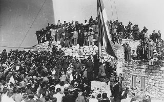 Αθήνα, 18 Οκτωβρίου 1944. Ο πρωθυπουργός Γ. Παπανδρέου υψώνει τη γαλανόλευκη στον Ιερό Βράχο. Μέσω του σχηματισμού κυβέρνησης εθνικής ενότητας προσπάθησε να αποτρέψει τον εμφύλιο πόλεμο.