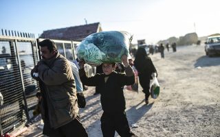 A child carries a bag on his head as Syrians fleeing the northern embattled city of Aleppo wait at the Bab al-Salama crossing on the border between Syria and Turkey, on February 5, 2016. Nearly 40,000 Syrian civilians have fled a regime offensive near Aleppo, a monitor said, as Turkey warned it was bracing for a wave of tens of thousands of refugees. / AFP / BULENT KILIC