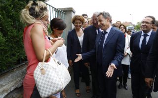 Αχου το! Ροζ φόρεμα, κλάμερ στο μαλλί, σινιέ τσάντα και το κινητό κολλημένο στο αυτί. Ο Nicola Sarkozy προσπαθεί να προσεγγίσει τις λαχτάρες της μεσαίας τάξης έξω από σχολείο στο Orgeval του Παρισιού στην διάρκεια προεκλογικής εκστρατείας του. AFP / POOL / PATRICK KOVARIK