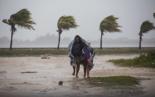 A woman and child use a blanket as protection from wind and rain as they walk in Caibarien, Cuba, Friday, Sept. 8, 2017. Hurricane Irma battered Cuba on Saturday with deafening winds and unremitting rain, pushing seawater inland and flooding homes before taking aim at Florida. Early Saturday, the hurricane center said the storm was centered about 10 miles (15 kilometers) northwest of the town of Caibarien. (AP Photo/Desmond Boylan)