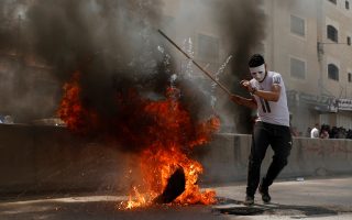 A Palestinian demonstrator reacts next to a burning tire during a protest against U.S. embassy move to Jerusalem and ahead of the 70th anniversary of Nakba, near Israeli Qalandia checkpoint near Ramallah in the occupied West Bank May 14, 2018. REUTERS/Mohamad Torokman     TPX IMAGES OF THE DAY