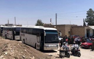In this photo released by the Syrian official news agency SANA, buses arrive in Tel el-Eis, the crossing between Aleppo and Idlib provinces, Syria, Wednesday, July 18, 2018. About 7,000 Syrians were expected to be evacuated from the two pro-government villages of Foua and Kfarya, ending their three-year siege by insurgents who control the surrounding areas. (SANA via AP)