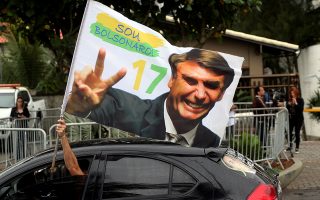 Oπαδός του Ζαΐρ Μπολσονάρο πανηγυρίζει κρατώντας σημαία που εικονίζει τον νέο πρόεδρο της Βραζιλίας.
