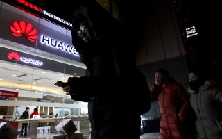 People walk past a Huawei retail shop in Beijing Thursday, Dec. 6, 2018. China on Thursday demanded Canada release a Huawei Technologies executive who was arrested in a case that adds to technology tensions with Washington and threatens to complicate trade talks. (AP Photo/Ng Han Guan)