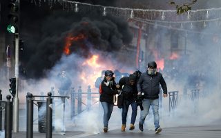 People run away from a burning car during clashes, Saturday, Dec. 8, 2018 in Marseille, southern France. The grassroots movement began as resistance against a rise in taxes for diesel and gasoline, but quickly expanded to encompass frustration at stagnant incomes and the growing cost of living. (AP Photo/Claude Paris)