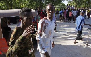 A civilian who was wounded in suicide car bomb attack is helped by a friend at check point in Mogadishu, Somalia, Saturday, Dec, 28, 2019. A police officer says a car bomb has detonated at a security checkpoint during the morning rush hour in Somalia's capital. (AP Photo/Farah Abdi Warsame)