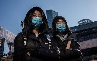People wear protective masks as they walk outside a shopping mall in Beijing on January 23, 2020. - China is halting public transport and closing highway toll stations in two more cities in Hubei province, the epicentre of a deadly virus outbreak, authorities said on January 23. (Photo by NICOLAS ASFOURI / AFP)