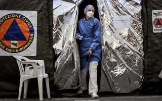 A paramedic wearing a mask gets out of a tent set up by the Italian Civil Protection outside the emergency ward of the Piacenza hospital, northern Italy, Thursday, Feb. 27, 2020. Italy is changing how it reports coronavirus cases and who will get tested in ways that could lower the country's caseload even as an outbreak centered in northern Italy spreads in Europe. (Claudio Furlan/Lapresse via AP)