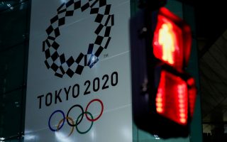 FILE PHOTO : A banner for the upcoming Tokyo 2020 Olympics is seen through a traffic signal in Tokyo, Japan, March 11, 2020. REUTERS/Issei Kato/File Photo