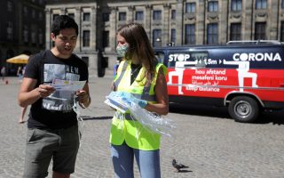 FILE PHOTO: A woman wearing a yellow vest hands out masks and information brochures where to wear the mandatory masks in the busiest streets of the city, during the coronavirus disease (COVID-19) outbreak, in Amsterdam, Netherlands August 5, 2020. REUTERS/Eva Plevier/File Photo