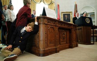 Sammy Olszta, 6, grandson of U.S. Olympic wrestling Gold Medalist and Presidential Medal of Freedom recipient Dan Gable, leans against the Resolute Desk as Gable delivers remarks beside U.S. President Donald Trump during a presentation ceremony inside the Oval Office at the White House in Washington, U.S., December 7, 2020. REUTERS/Tom Brenner