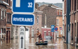 Ανδρας οδηγεί τη βάρκα του στους πλημμυρισμένους δρόμους προαστίου της Λιέγης. Το καλοκαίρι του 2021, πλημμύρες έπληξαν το Βέλγιο, τη Γερμανία και άλλες χώρες της Κεντρικής Ευρώπης με δεκάδες νεκρούς. Φωτ. A.P. / Valentin Bianchi